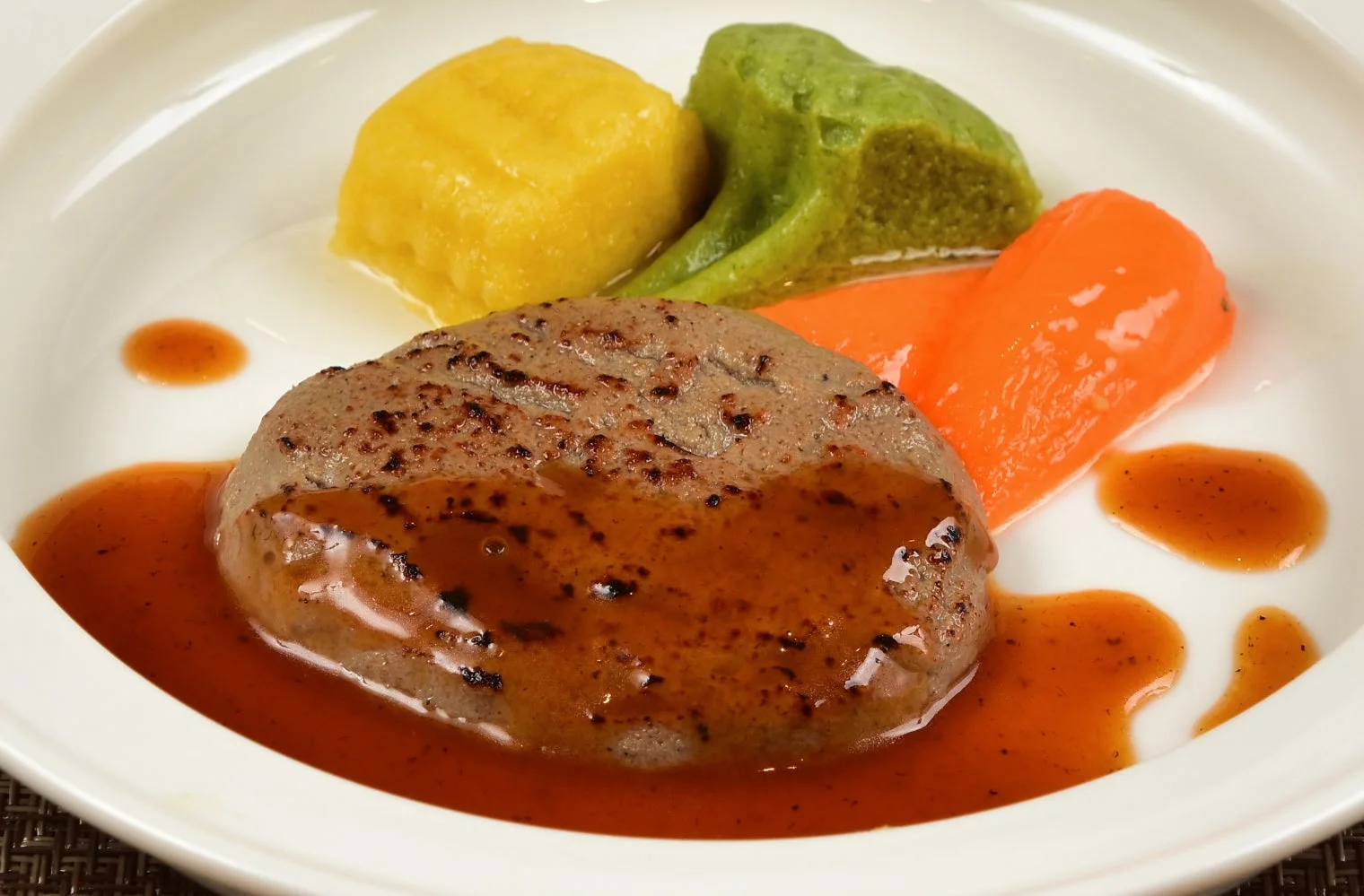 濃厚なソースがかかった肉料理とマッシュ野菜が盛り付けられた洋食