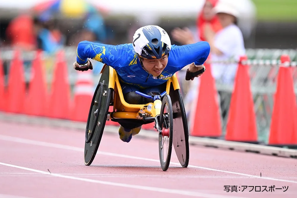 競技用車いすに乗ったアスリートが、トラックを力強く走行している様子