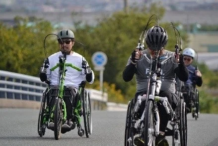 屋外の道路でハンドサイクルに乗って競技またはトレーニングをするアスリート
