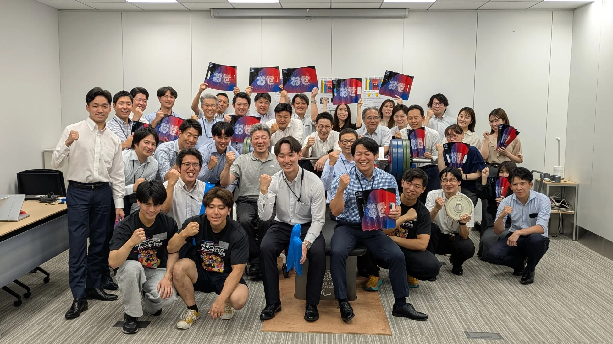 オフィスで応援する社員たちの集合写真