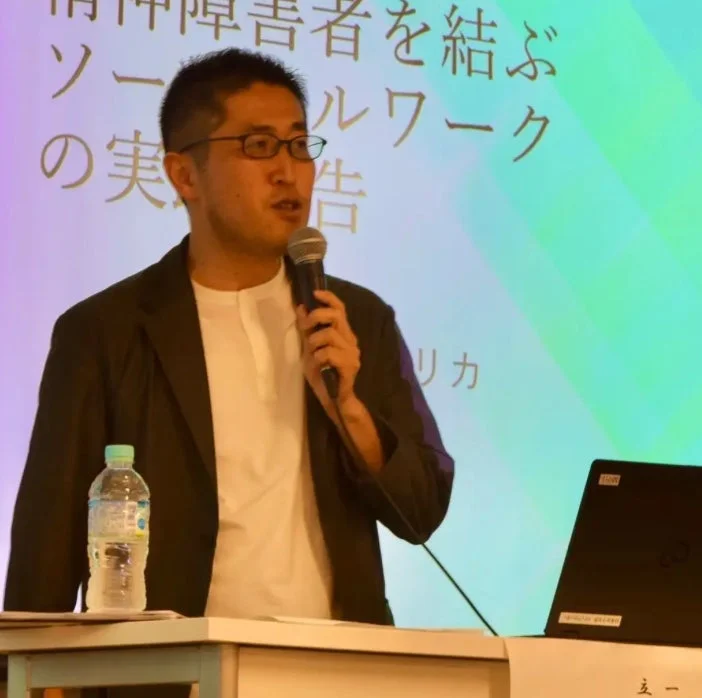 イメージ画像:マイクを手に講演中の男性