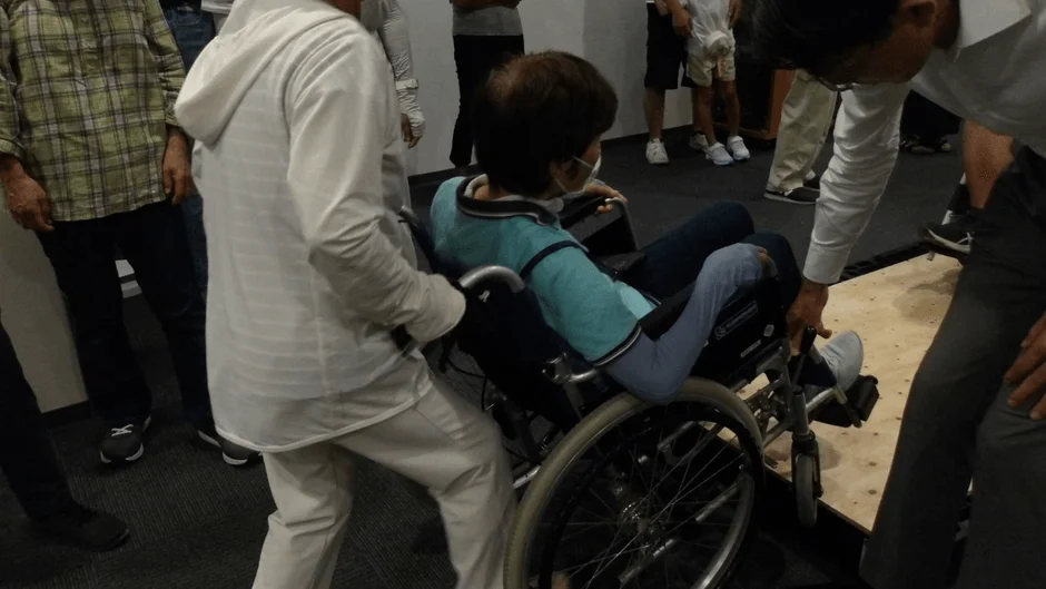 車椅子を介助する人々