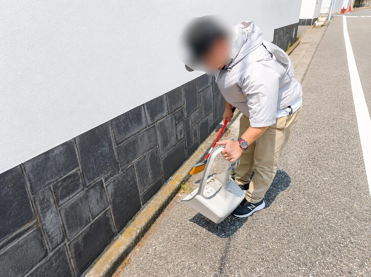 男性がほうきで清掃する様子
